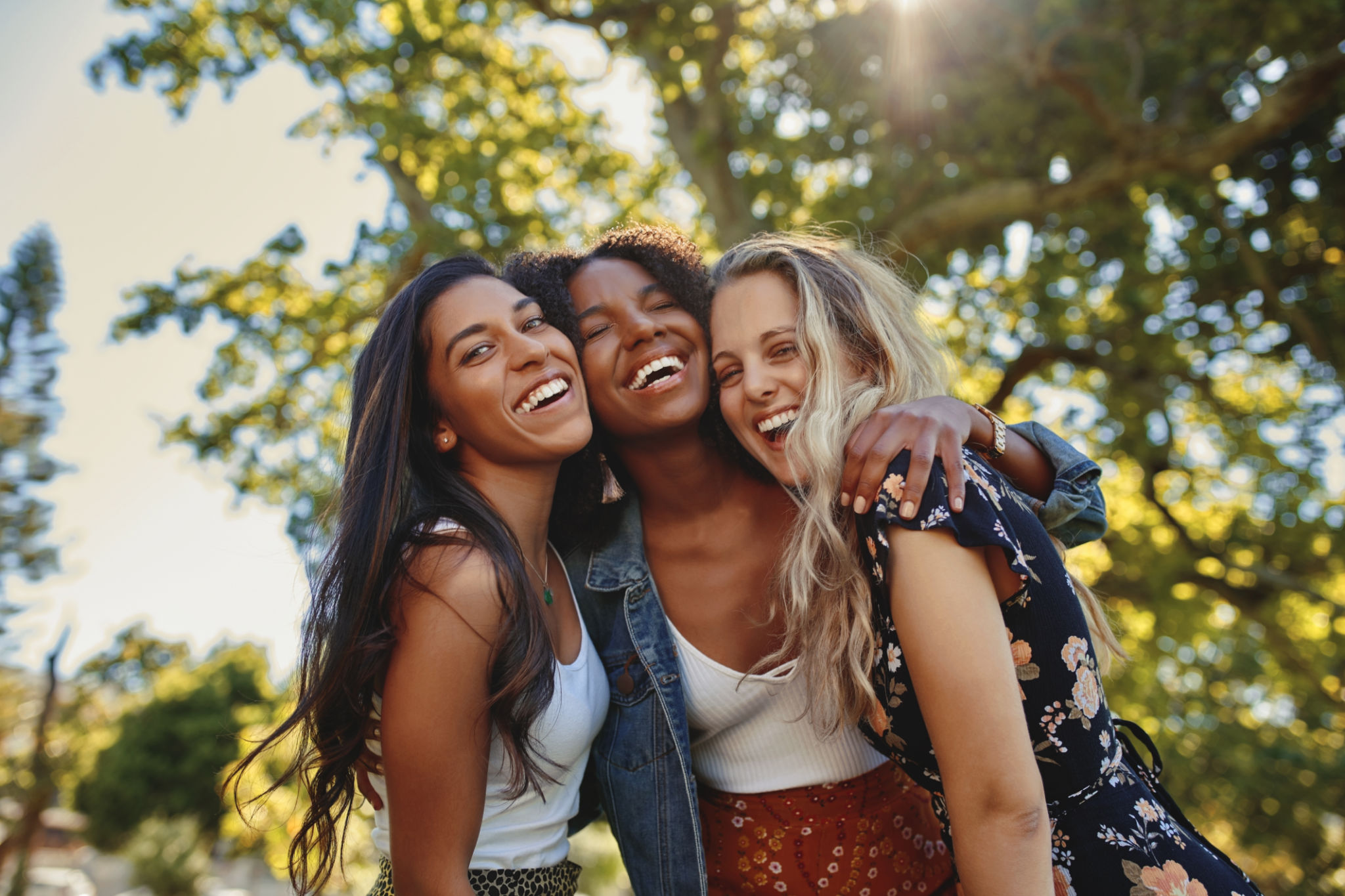 Portrait of a happy multiethnic group of smiling female friends - women laughing and having fun in the park on a sunny day Portrait of a happy multiethnic group of smiling female friends - women laughing and having fun in the park on a sunny day