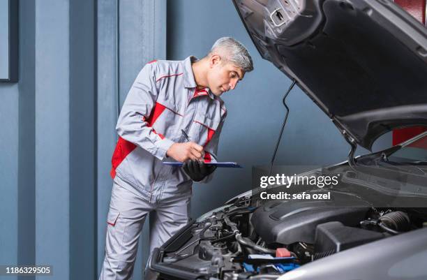 modulo di assistenza meccanico automatico che compila il motore in auto - auto repair shop foto e immagini stock