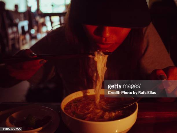 young woman eating noodles in low light - hot vietnamese women stock pictures, royalty-free photos & images
