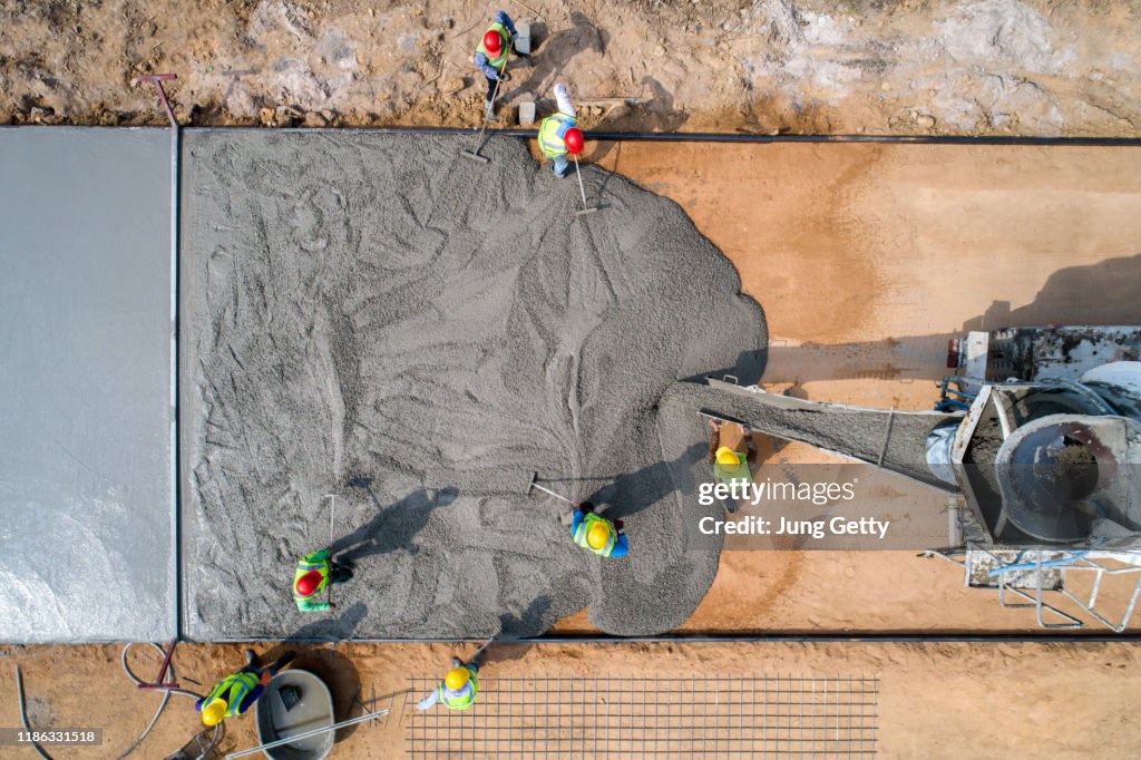 A construction worker pouring a wet concret at road construction site