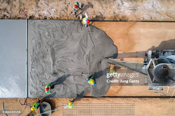 a construction worker pouring a wet concret at road construction site - cimento imagens e fotografias de stock