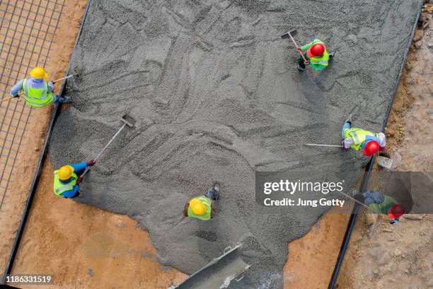 a construction worker pouring a wet concret at road construction site - aerial view construction workers stock-fotos und bilder