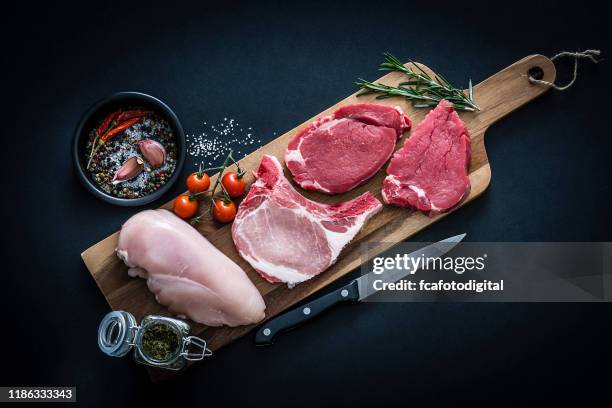 rohes fleischsortiment - rinder-, hühner- und schweinekoteletts von oben auf dunklem hintergrund - beef steak stock-fotos und bilder