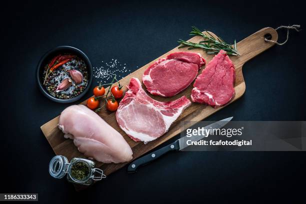 surtido de carne cruda - chuletas de carne de res, pollo y cerdo rodadas desde arriba sobre fondo oscuro - cerdo fotografías e imágenes de stock