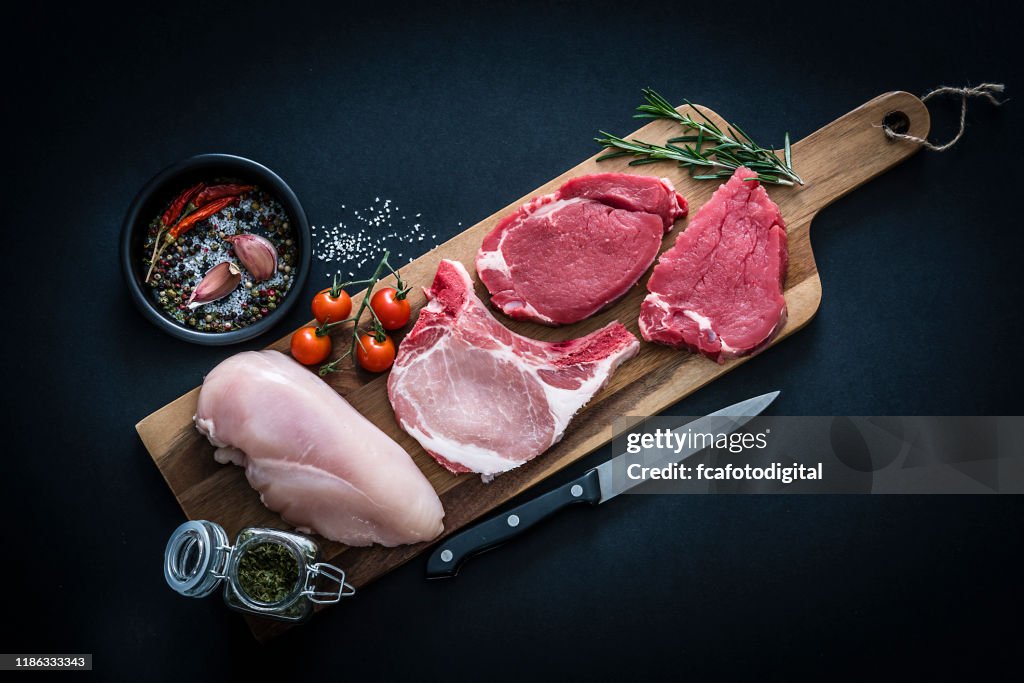 Rauw vlees assortiment-rundvlees, kip en Varkenskarbonades geschoten van bovenaf op donkere achtergrond