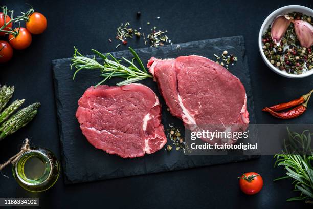 due bistecche di filetto crude girate dall'alto su un tavolo scuro - filetto foto e immagini stock