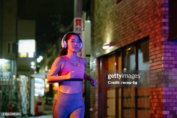 young female athlete running in city at night - asia rain stock pictures, royalty-free photos & images