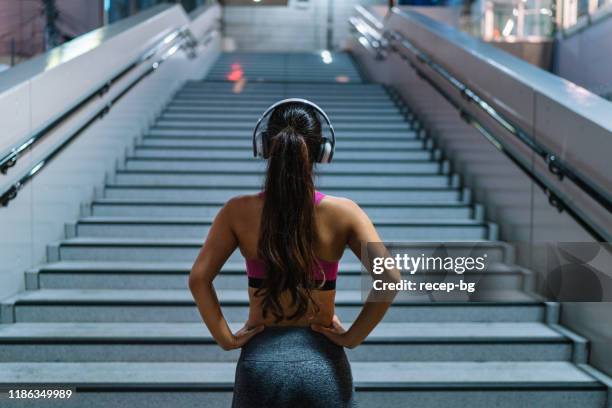 female athlete standing in front of stairs - portrait of young woman standing against steps stock pictures, royalty-free photos & images