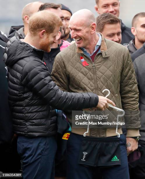 Prince Harry, Duke of Sussex jokes with Gareth Thomas after being presented with a Harlequins rugby kit for baby son Archie Harrison...