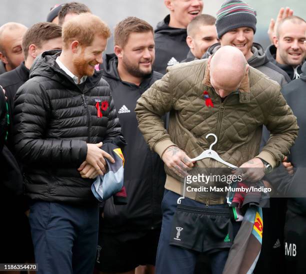 Prince Harry, Duke of Sussex jokes with Gareth Thomas after being presented with a Harlequins rugby kit for baby son Archie Harrison...