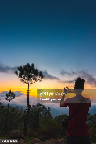 la femme tire la vue nuageuse de coucher du soleil dans les montagnes par un smartphone. - himachal pradesh photos et images de collection
