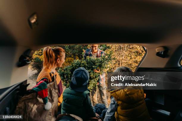 young family carrying home their christmas tree - xmas car stock pictures, royalty-free photos & images