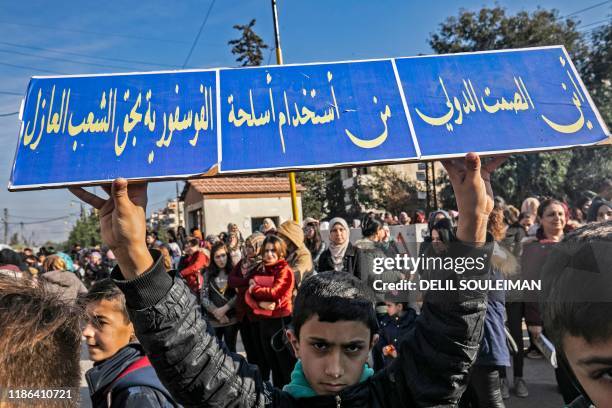 Pupil lifts a placard during a demonstration of elementary and secondary schoolchildren in front of United Nations offices in the Syrian...