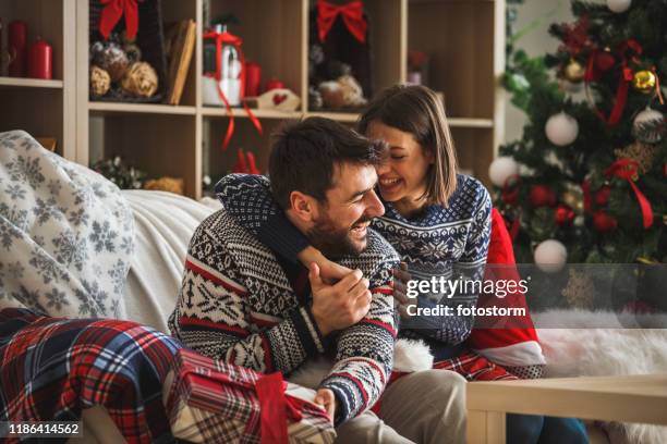 couple hugging and laughing while enjoying winter holiday at home - hug christmas stock pictures, royalty-free photos & images