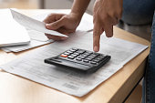 Close up female hands holding receipt calculating incomes doing paperwork
