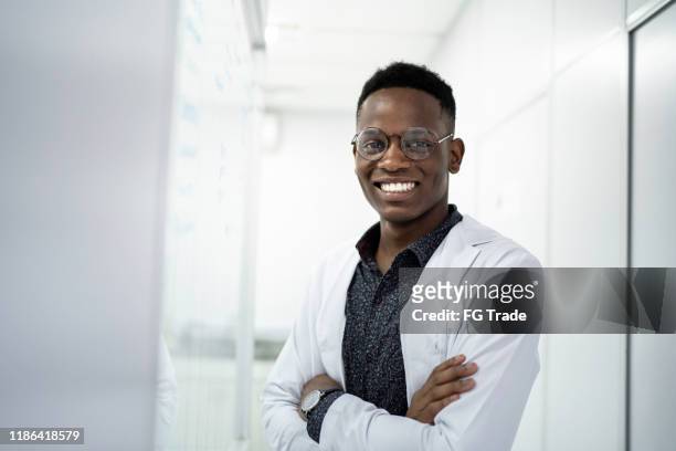 verticale d'un scientifique de sourire au laboratoire - blouse de laborantin photos et images de collection