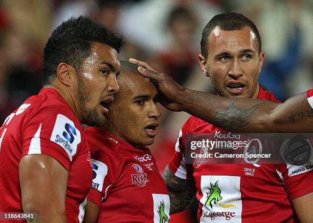 Digby Ioane and Quade Cooper of the Reds congratulate team mate Will Genia after scoring a try during the 2011 Super Rugby Grand Final match between...