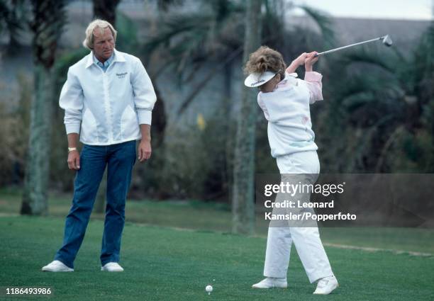 Australian golfer Greg Norman watches as his wife Laura Andrassy hits a tee shot, circa 1987.