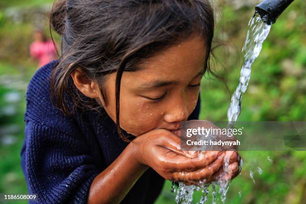nepali mädchen trinkwasser, dorf in der nähe von annapurna range - quellwasser stock-fotos und bilder