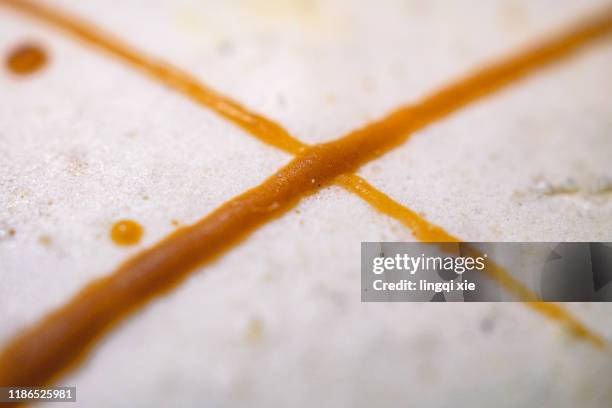 a syrup-painted x-shaped pattern on a macaron. - blunt pencil stock pictures, royalty-free photos & images