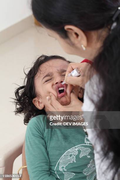 administering oral poliovirus vaccine to little boy - polio stockfoto's en -beelden