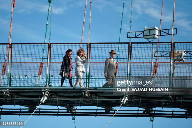 Sweden's King Carl XVI Gustaf and Queen Silvia walk on the Ram Jhula bridge over Ganga river in Rishikesh on December 5, 2019.