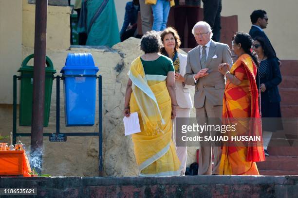 Sweden's King Carl XVI Gustaf and Queen Silvia speak with two female priests as they arrive to attend attend a Ganga Arti Puja, a prayer service, on...