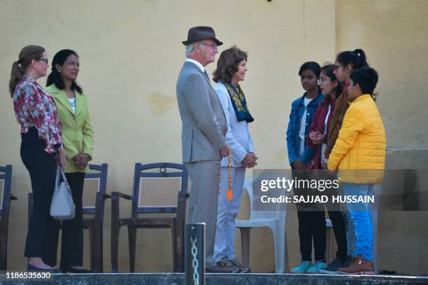Sweden's King Carl XVI Gustaf and Queen Silvia attend speak with children as they arrive to attend a Ganga Arti Puja, a prayer service, on the banks...