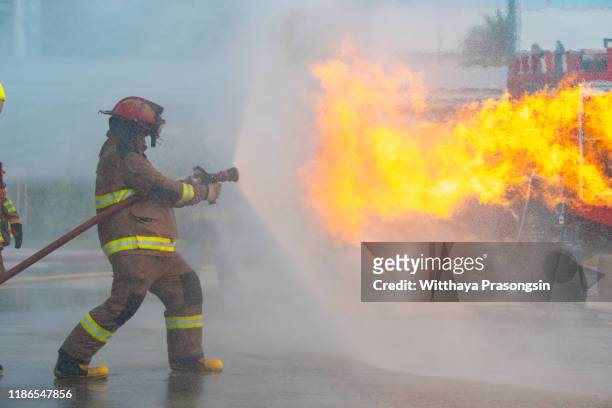 firefighter spraying water at a house fire - extinguishing stockfoto's en -beelden