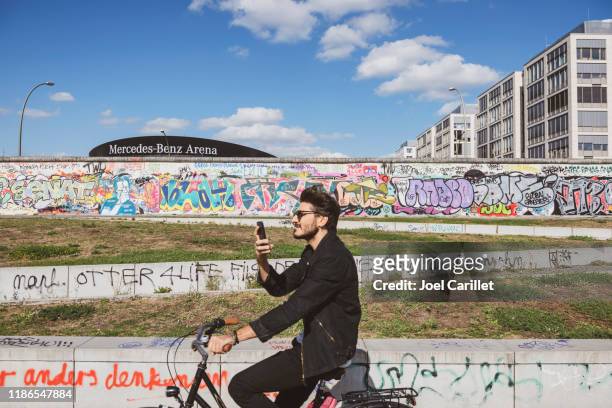 fietsen in berlijn aan de east side gallery berlin wall - mercedes benz arena berlijn stockfoto's en -beelden