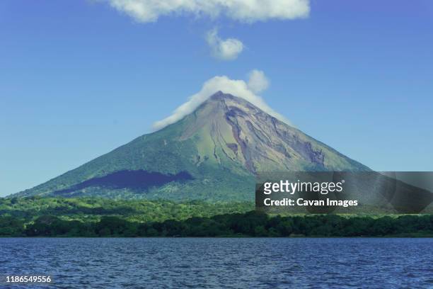 scenic view of lake nicaragua by mountain against blue sky - nicaragua fotografías e imágenes de stock