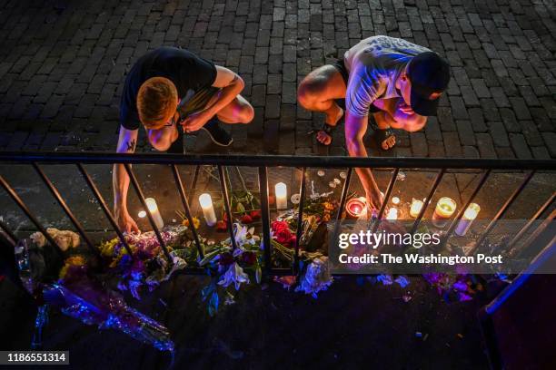 Samuel Klug, L, and John Neff place candles around a makeshift memorial at the scene of a mass shooting in the city's historic Oregon District where...