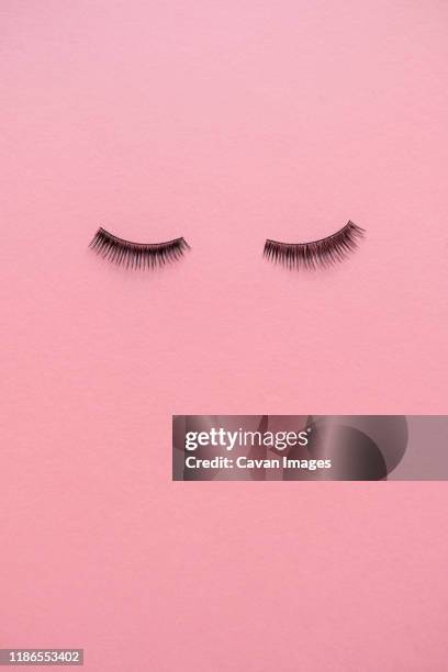 high angle view of false eyelashes on pink table - eyelash extensions stock pictures, royalty-free photos & images