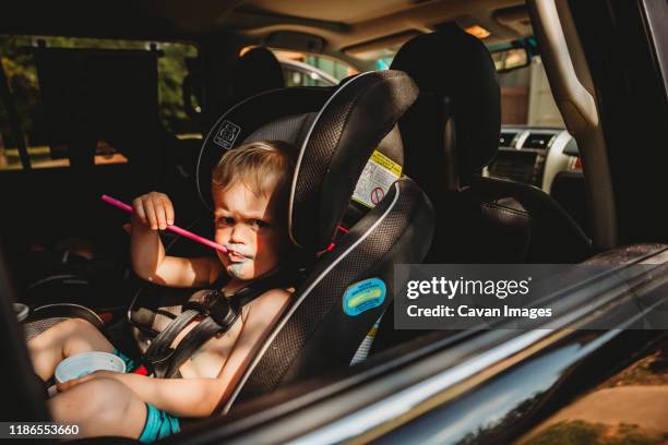 young boy with grumpy face drinking from straw in car seat - messy car interior stock pictures, royalty-free photos & images