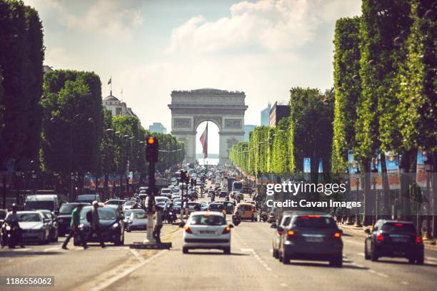 vehicles on road amidst trees against arc de triomphe in city - champs elysees quarter stock pictures, royalty-free photos & images
