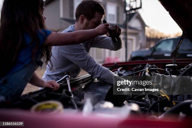 daughter assisting father in repairing car - car in driveway stock-fotos und bilder