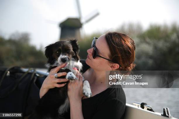 a young woman playing with her dog on a boat along the canal. - sunglasses and puppies stock pictures, royalty-free photos & images