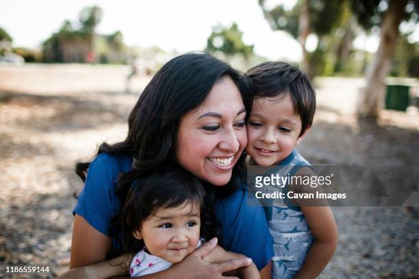 happy mother playing with children at park - gezin met twee kinderen stockfoto's en -beelden