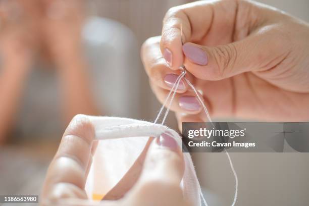 close-up view of women sewing - mani fili foto e immagini stock