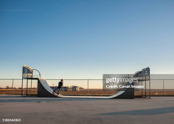 pullback of boy riding half pipe ramp on hoverboard against blue sky - half pipe stock pictures, royalty-free photos & images