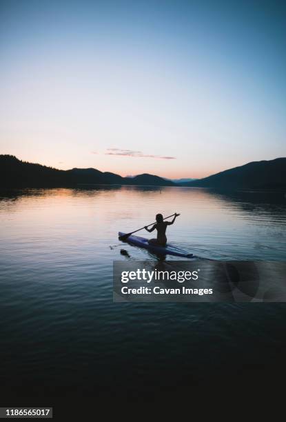 silhouette woman paddleboarding in lake against sky during sunset - montana black stock pictures, royalty-free photos & images