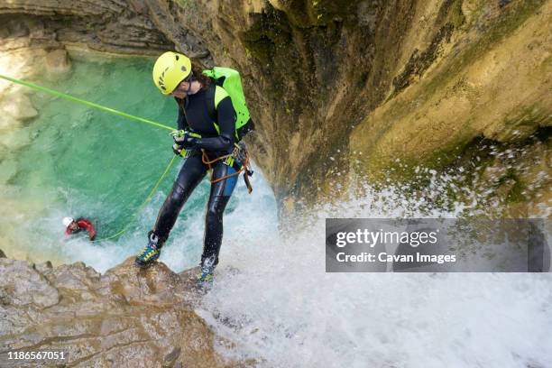 high angle view of hikers rappelling amidst waterfall on canyons - canyoning stock pictures, royalty-free photos & images