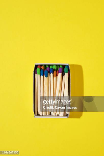 overhead view of colorful matchsticks in box on yellow background - streichholz stock-fotos und bilder