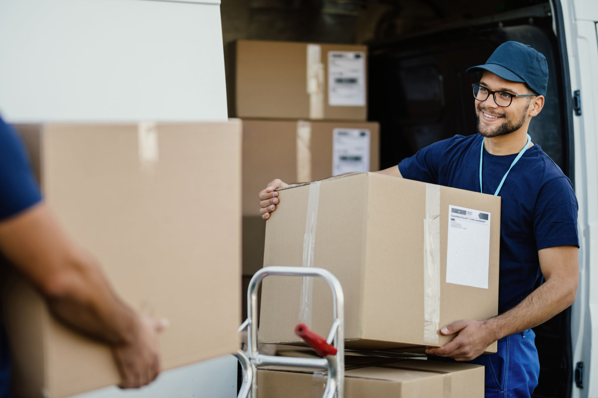 Happy manual worker unloading cardboard boxes from delivery van. Happy manual worker unloading cardboard boxes from delivery van.