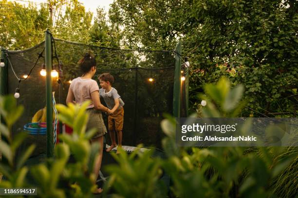 mama und sohn springen zusammen auf einem trampolin - trampoline stock-fotos und bilder