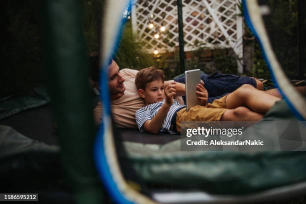 watching cartoons together, while lying on a trampoline - man trampoline stock pictures, royalty-free photos & images