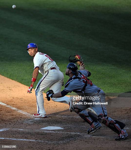 Raul Ibanez of the Philadelphia Phillies runs towards first base as Brian McCann of the Atlanta Braves goes for the ball at Citizens Bank Park on...