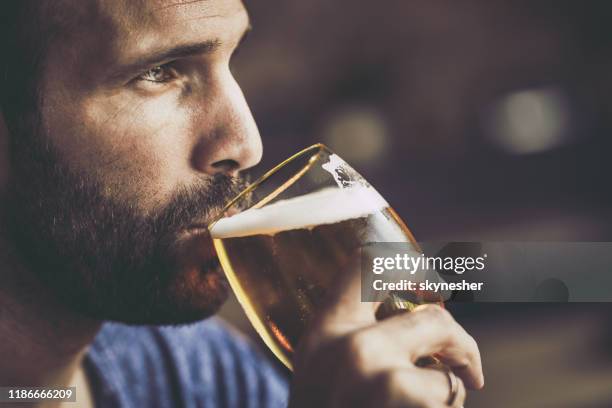 nahaufnahme von nachdenklichen mittleren erwachsenen mann trinken bier in einer kneipe. - beer close up stock-fotos und bilder