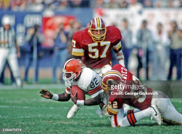 Linebacker Neal Olkewicz of the Washington Redskins tackles tight end Ozzie Newsome of the Cleveland Browns as linebacker Rick Milot looks on during...