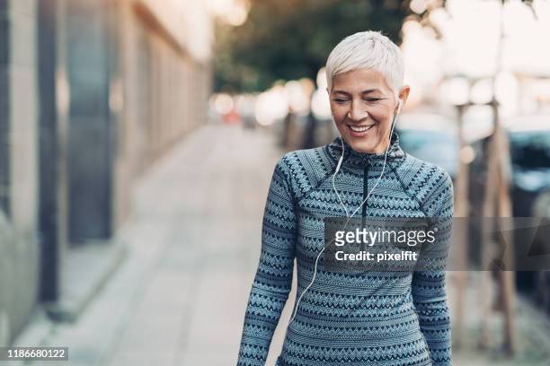 senior sportswoman walking on the street - active lifestyle stock pictures, royalty-free photos & images